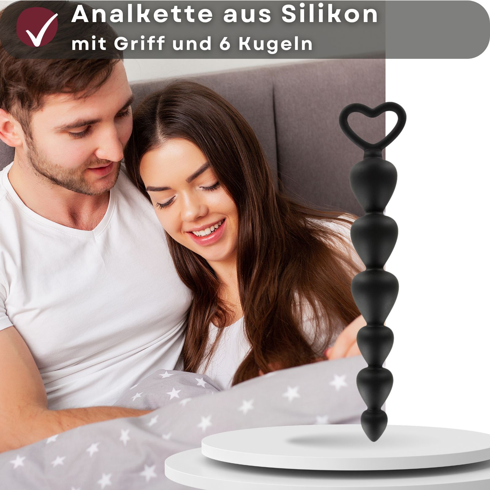 Schwarze Analperlenkette mit 6 Kugeln und Herzgriff. Silikon. Hintergrund: Paar. Text: Anal Kette aus Silikon mit Griff und 6 Kugeln.