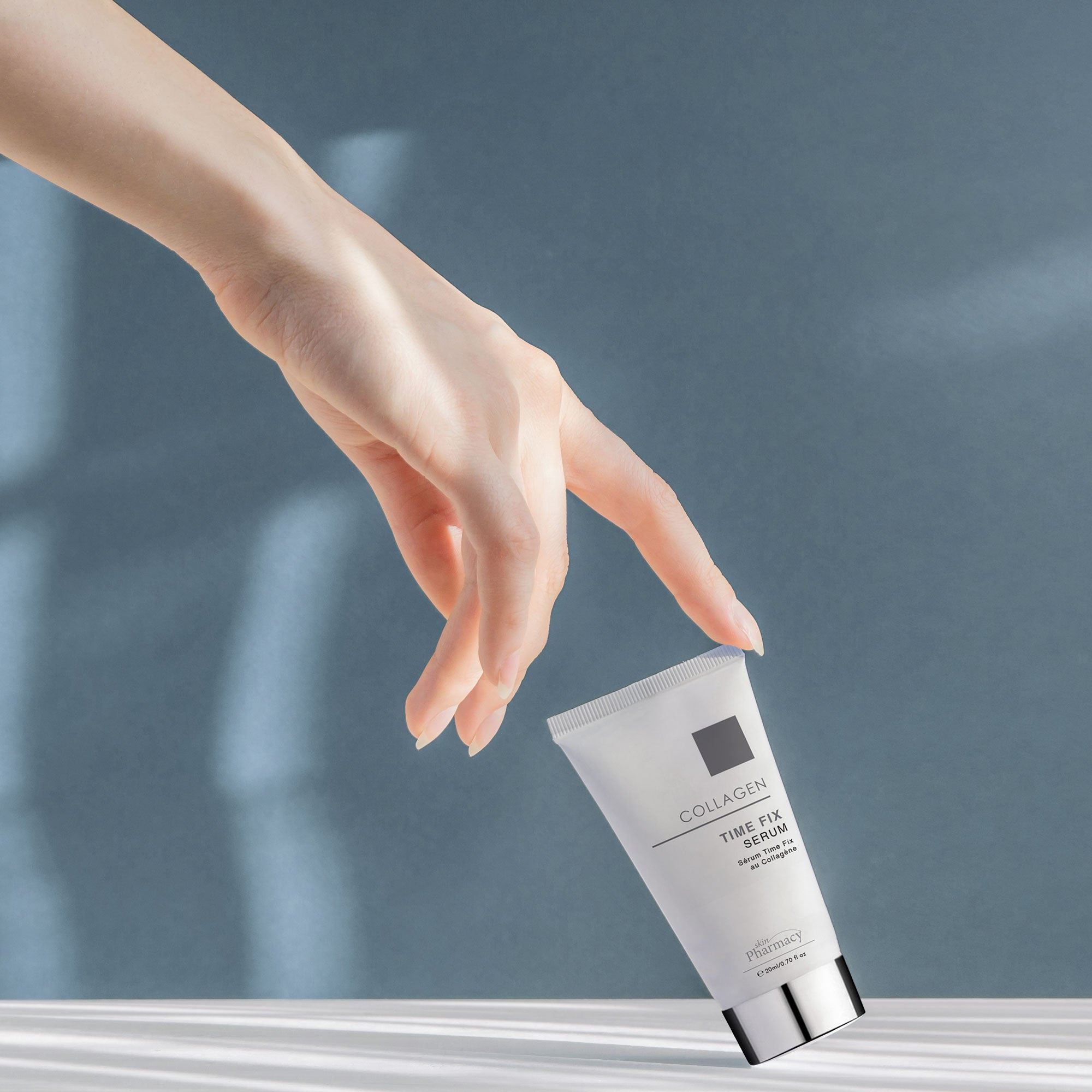 Hand lässt eine Tube skinPharmacy Collagen Time Fix Serum fallen.