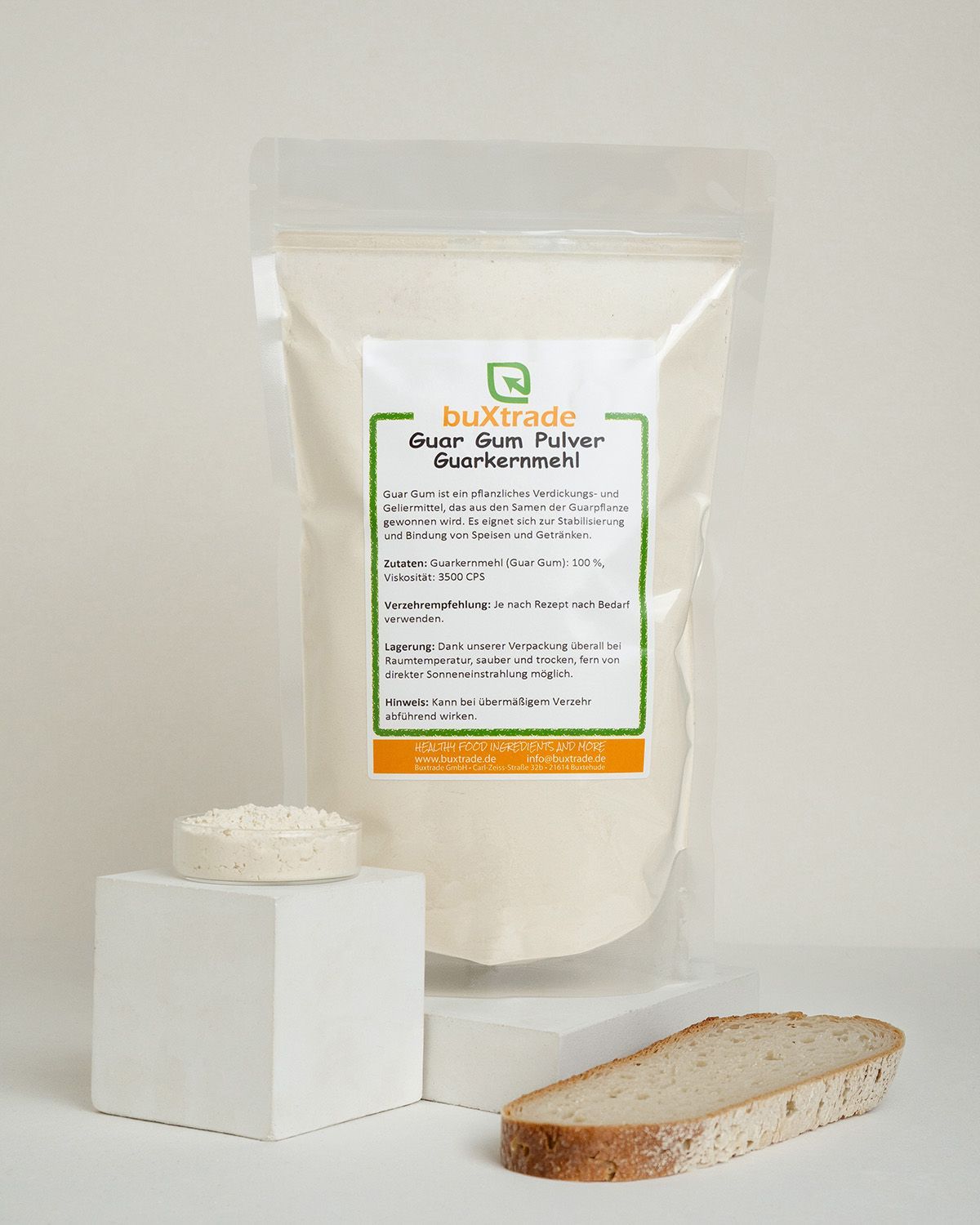 Verpackung mit Guarkernmehl Pulver, daneben eine Schale mit Pulver und Brotscheiben.