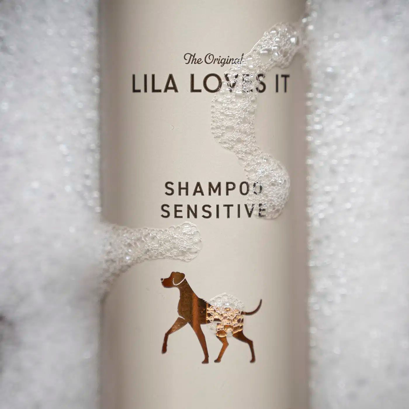 Nahaufnahme Shampoo Sensitive von LILA LOVES IT. Etikett mit Logo und Hund, umgeben von Schaum.