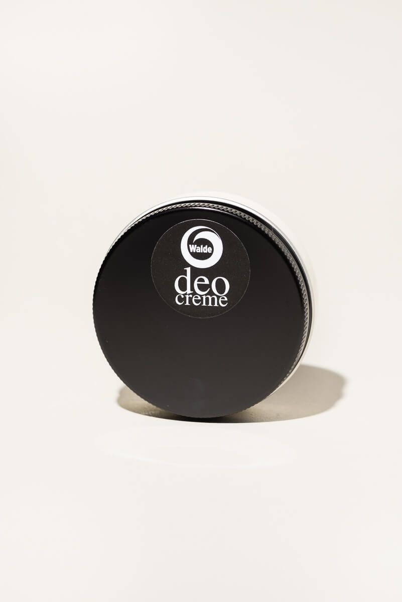 Runde Dose mit schwarzem Deckel. Auf dem Deckel befindet sich ein Aufkleber mit dem Logo und der Aufschrift "deo creme".