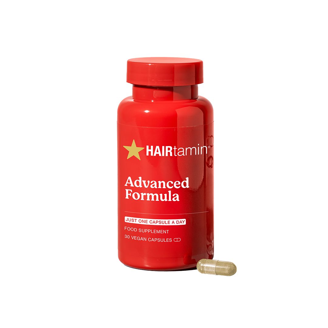 Rote Flasche HAIRtamin Advanced Formula. Aufschrift: Advanced Formula. Eine Kapsel daneben.