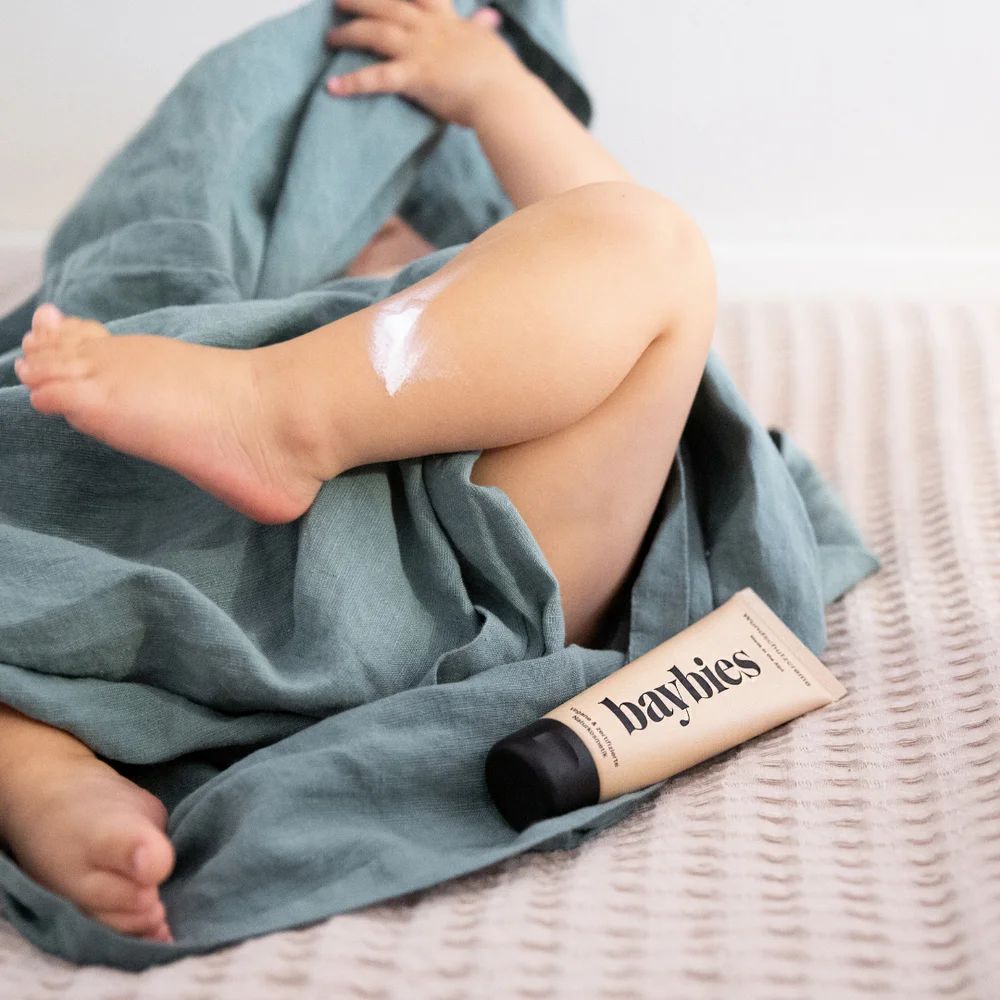 Babybein mit aufgetragener Wundschutzcreme, daneben eine Tube.