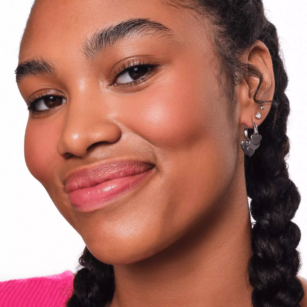 Porträt einer Frau mit gebräunter Haut. Rouge auf den Wangen. Rosa Lippen. Ohrringe.