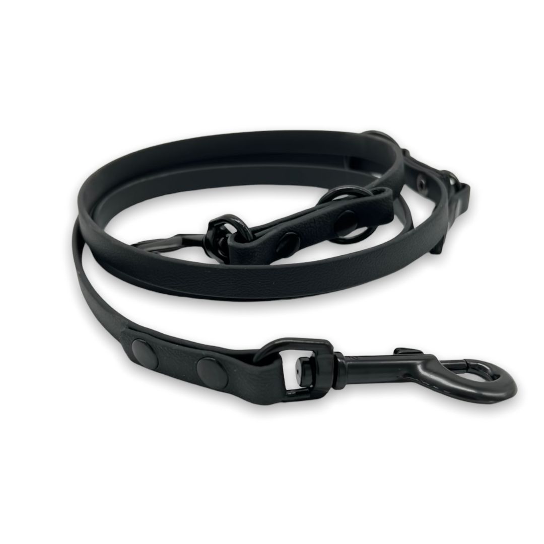 Schwarze Führleine aus BioThane®. Mit Karabinerhaken und Ring. Aufgerollt.