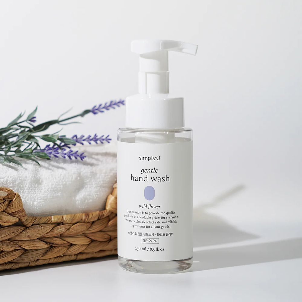 Transparente Flasche mit weißem Pumpkopf. Etikett mit Produktnamen und floralem Motiv. Auf Korb mit Handtuch und Lavendel.