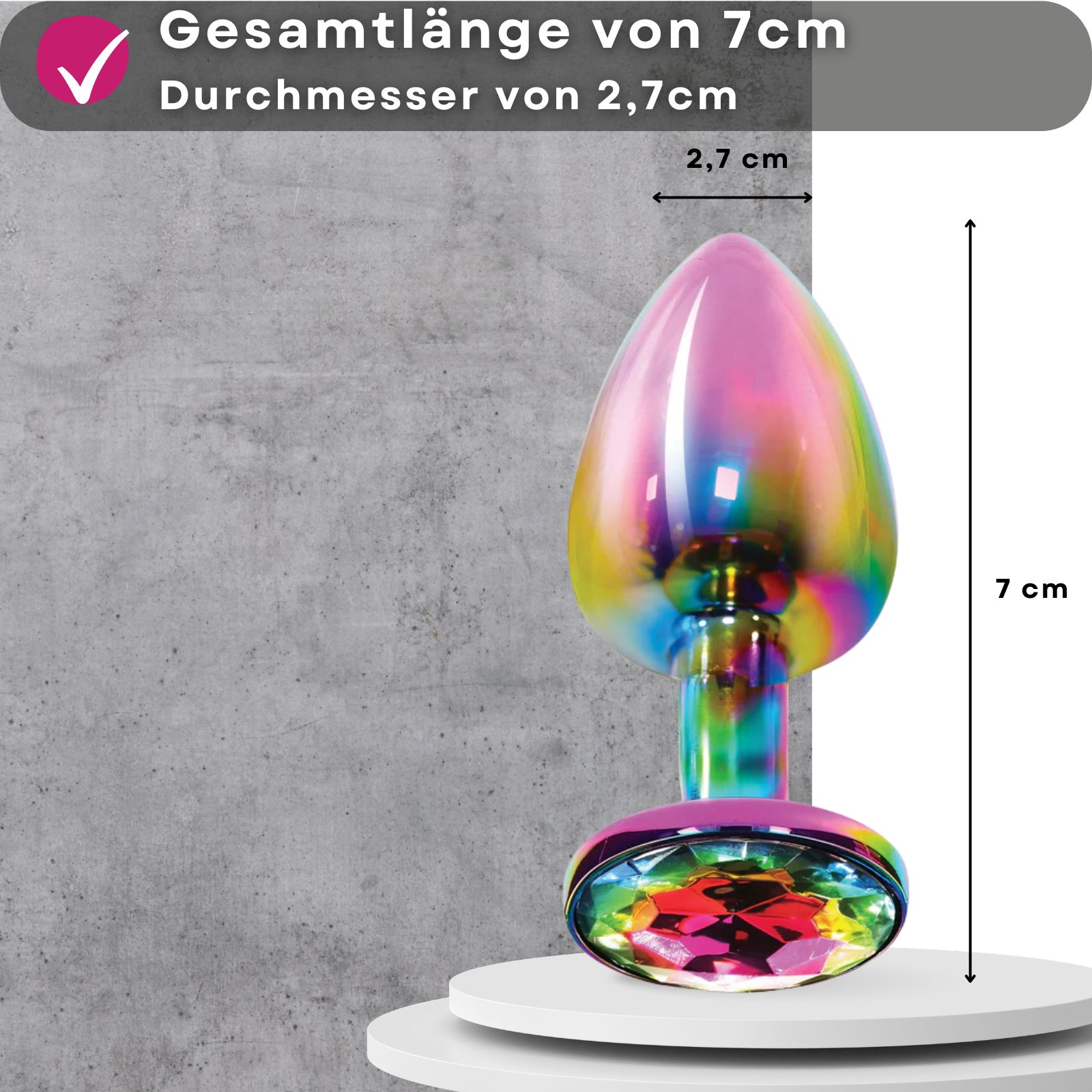 Analplug, mehrfarbig, aus Metall, mit Zierstein. Frau im Hintergrund. Produkt auf Podest.