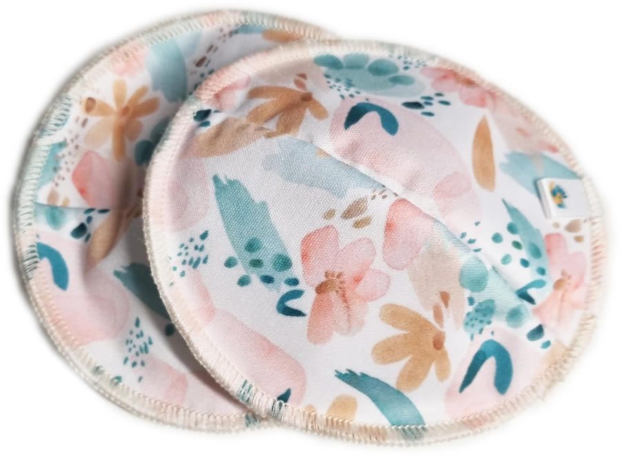 Zwei runde, waschbare Stilleinlagen mit floralem Muster in Rosa, Blau und Beige. Mit weißem Rand und kleinem Label.