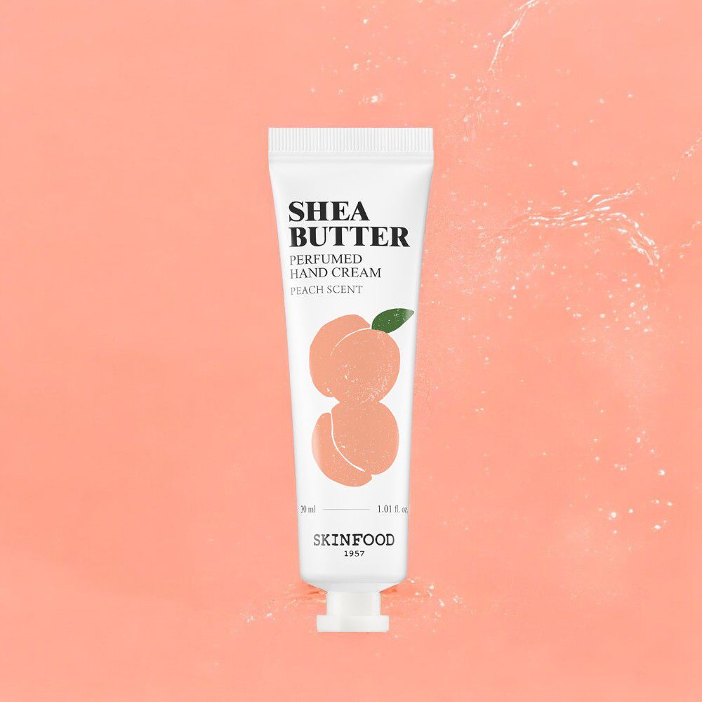 Weiße Handcreme-Tube mit SHEA BUTTER-Aufschrift, Pfirsich-Illustration, SKINFOOD-Logo, vor rosa Hintergrund.