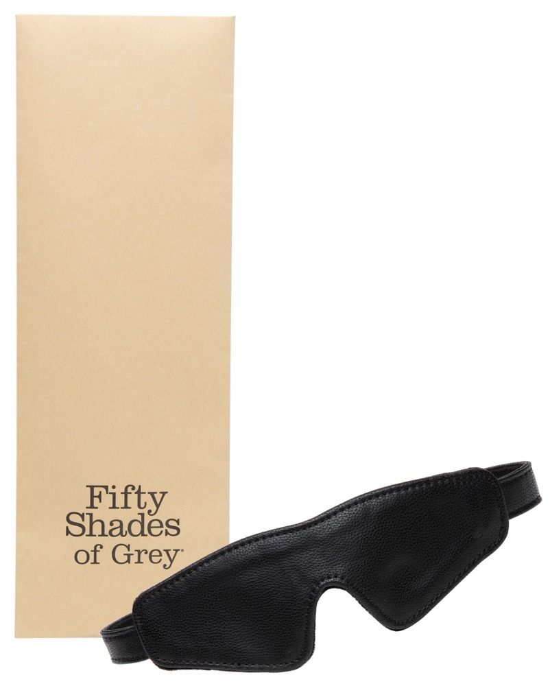 Schwarze Augenbinde mit Band. Neben einer braunen Verpackung mit "Fifty Shades of Grey"-Logo.