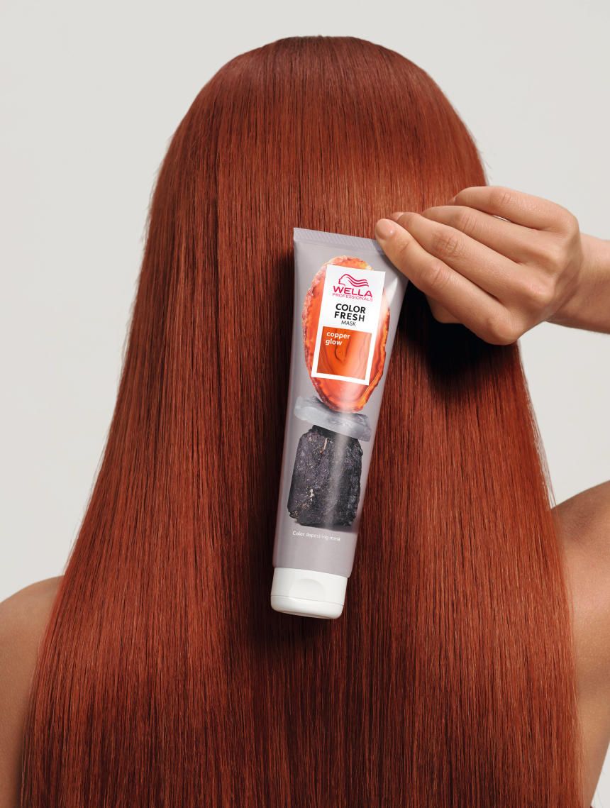 Person hält Tube Wella Color Fresh Mask Copper Glow an rotem Haar. Produktname und Logo sichtbar.