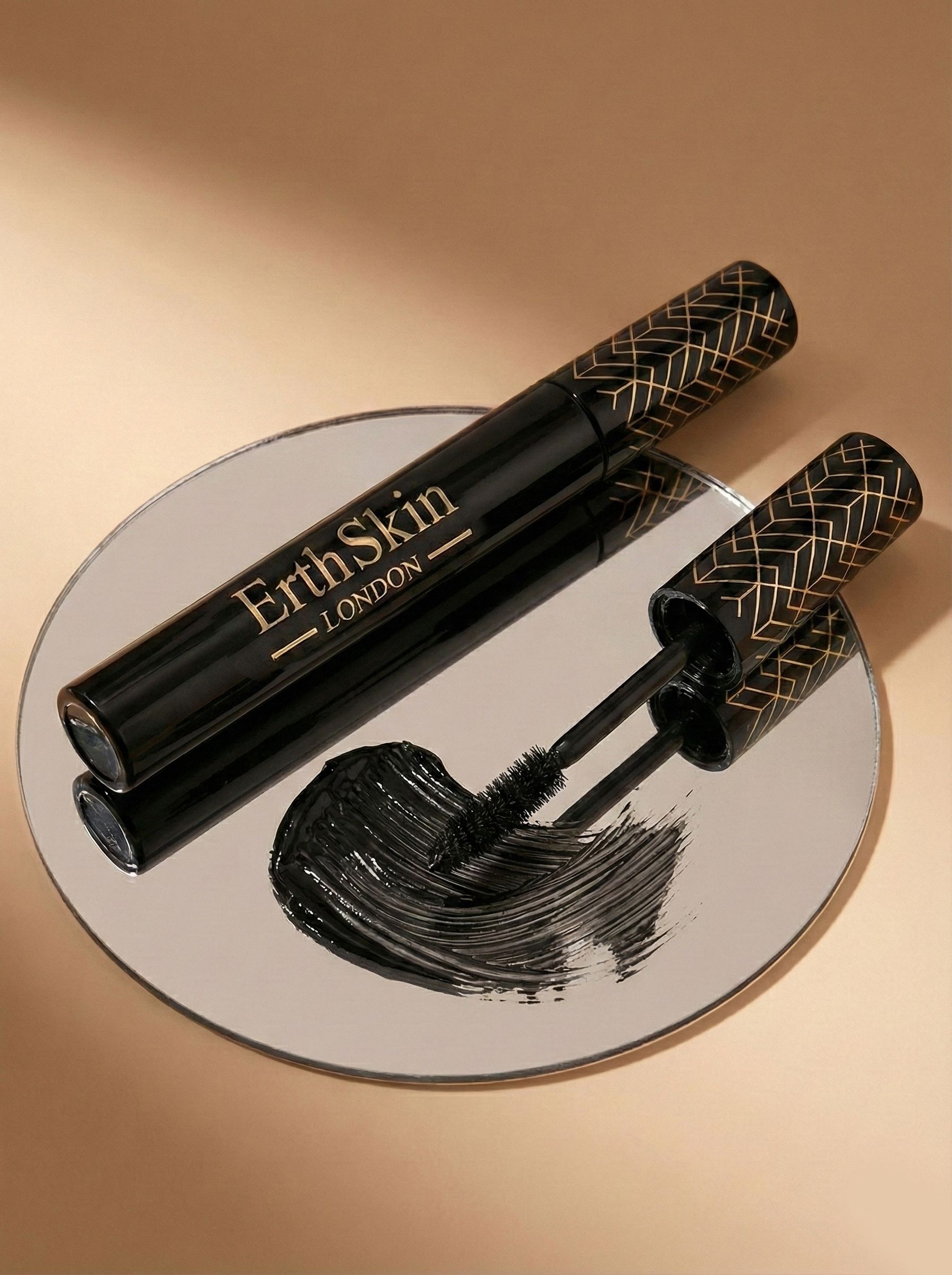 Schwarze Mascara mit goldener Schrift 'ErthSkin LONDON' auf einem Spiegel.