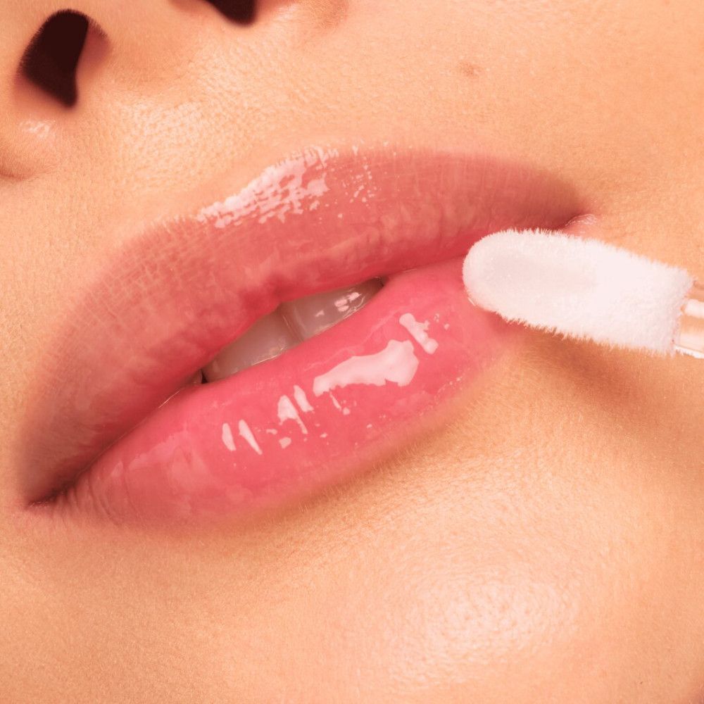 Nahaufnahme von Lippen, die mit Lipgloss aufgetragen werden. Applikator sichtbar.