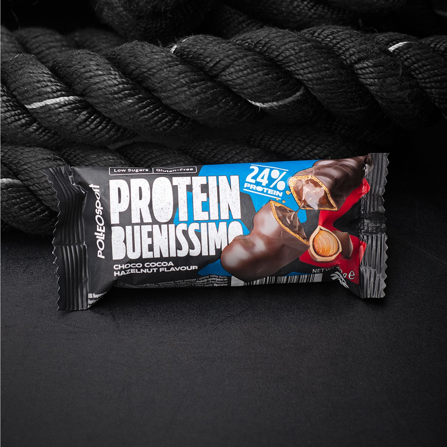Protein Buenissimo Riegel in Verpackung. Text: Choco Cocoa Hazelnut Flavour, 24% Protein, Low Sugars, Gluten-Free. Schwarzer Hintergrund.