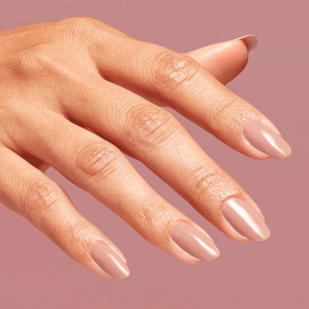 Hand mit lackierten Nägeln. Nagellack in hellem Roséton. Glänzendes Finish.