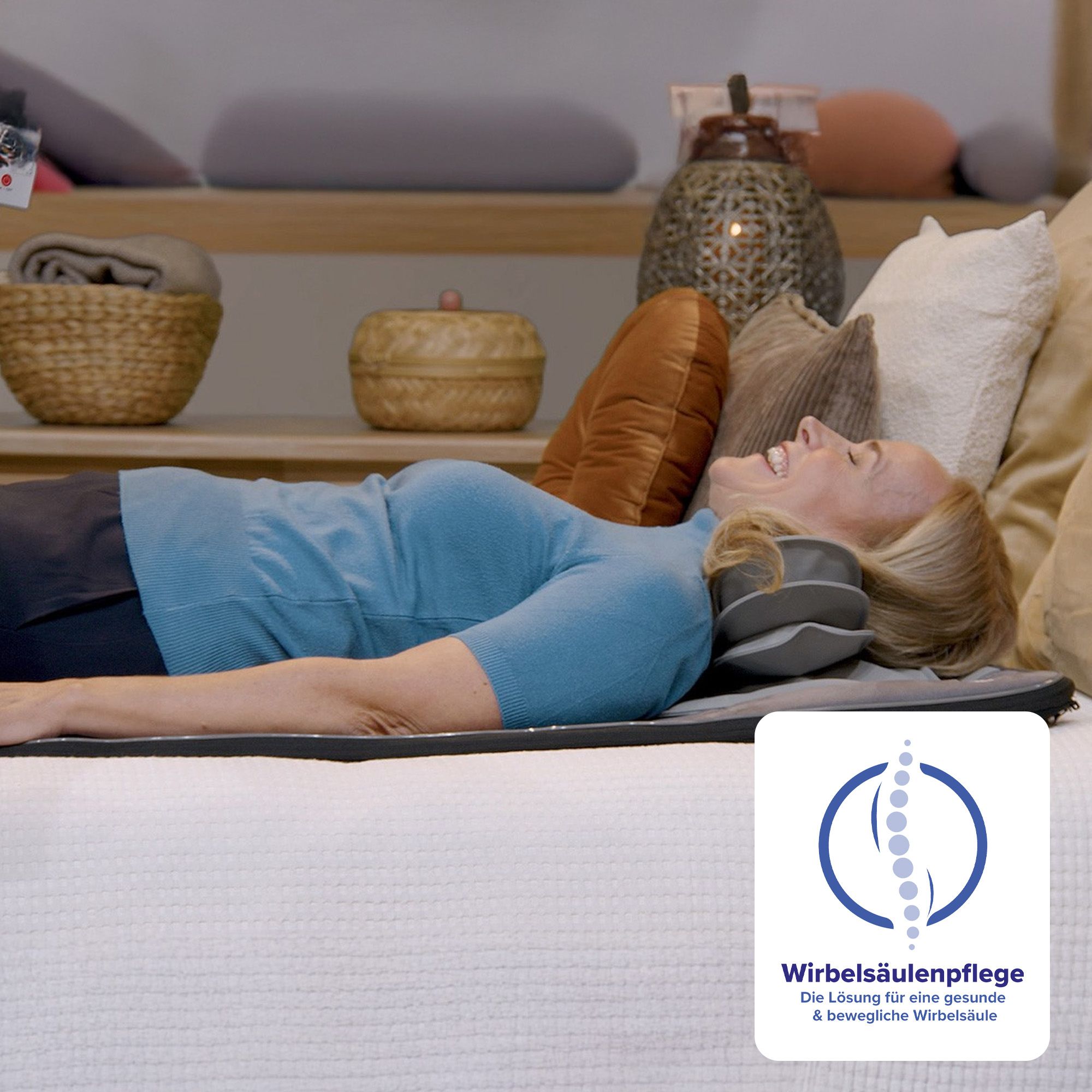 Frau liegt auf einer grauen Matte mit Kopfstütze. Aufschrift: Wirbelsäulenpflege. Hintergrund: Bett mit Kissen.