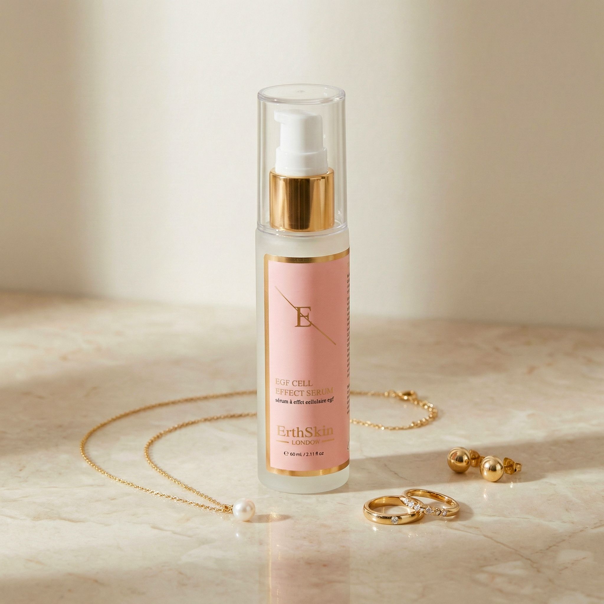 ErthSkin London EGF Serum neben Schmuck: Halskette, Ohrringe und Ringe auf Marmoroberfläche.