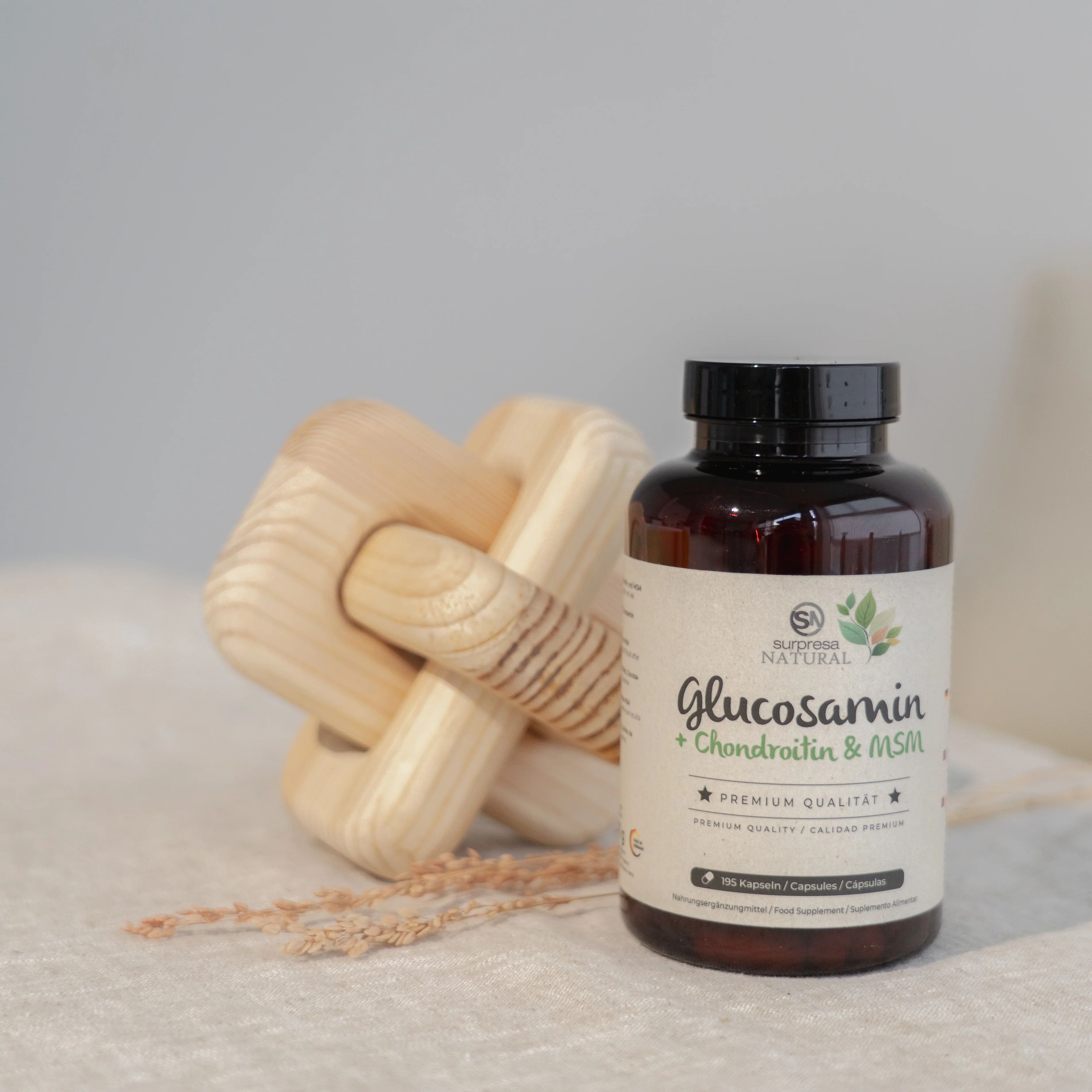 Braune Flasche mit Etikett. Aufschrift: Surpresa Natural Glucosamin + Chondroitin & MSM. Holzobjekt daneben.