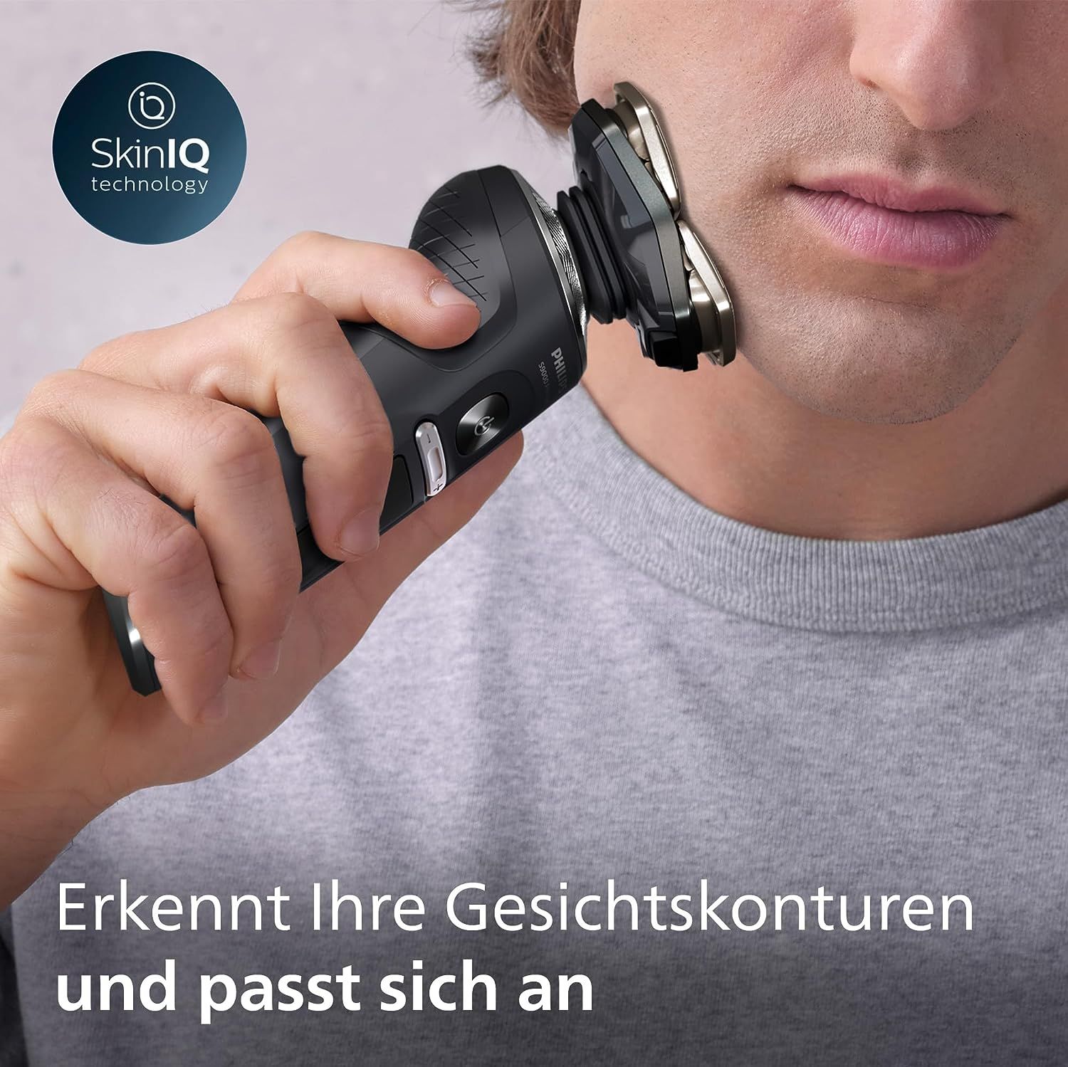 Mann rasiert sich mit schwarzem Rasierer. SkinIQ-Technologie-Logo. Text: Erkennt Ihre Gesichtskonturen und passt sich an.
