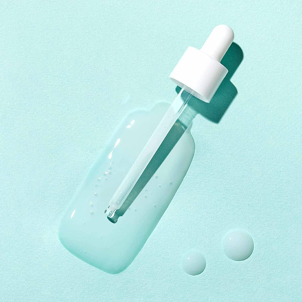 Durchsichtige Flüssigkeit mit Pipette auf hellblauem Hintergrund. Zwei Tropfen daneben.