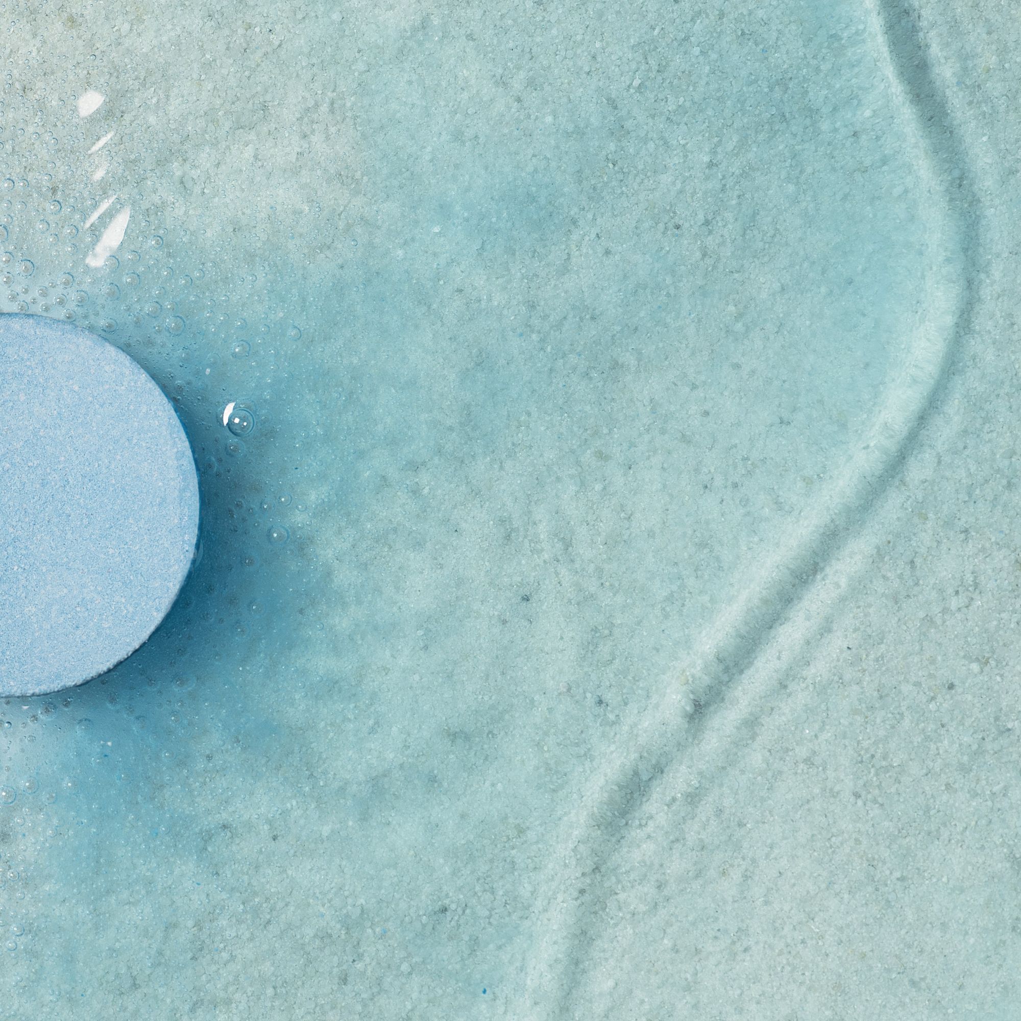 Nahaufnahme eines blauen Badezusatzes in Wasser. Wasser mit Blasen und Wellen.