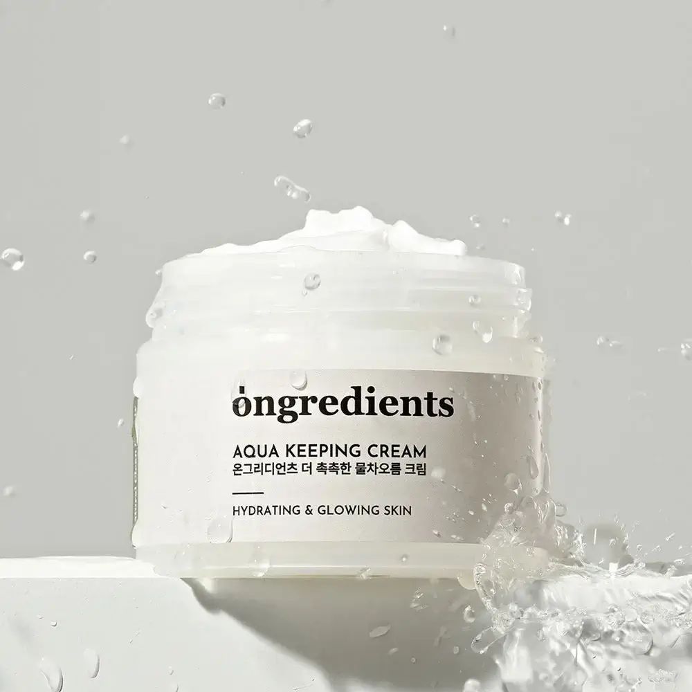 Creme-Glas mit silbernem Deckel, umgeben von Wasser. Aufschrift: Ongredients, Aqua Keeping Cream, Hydrating & Glowing Skin.