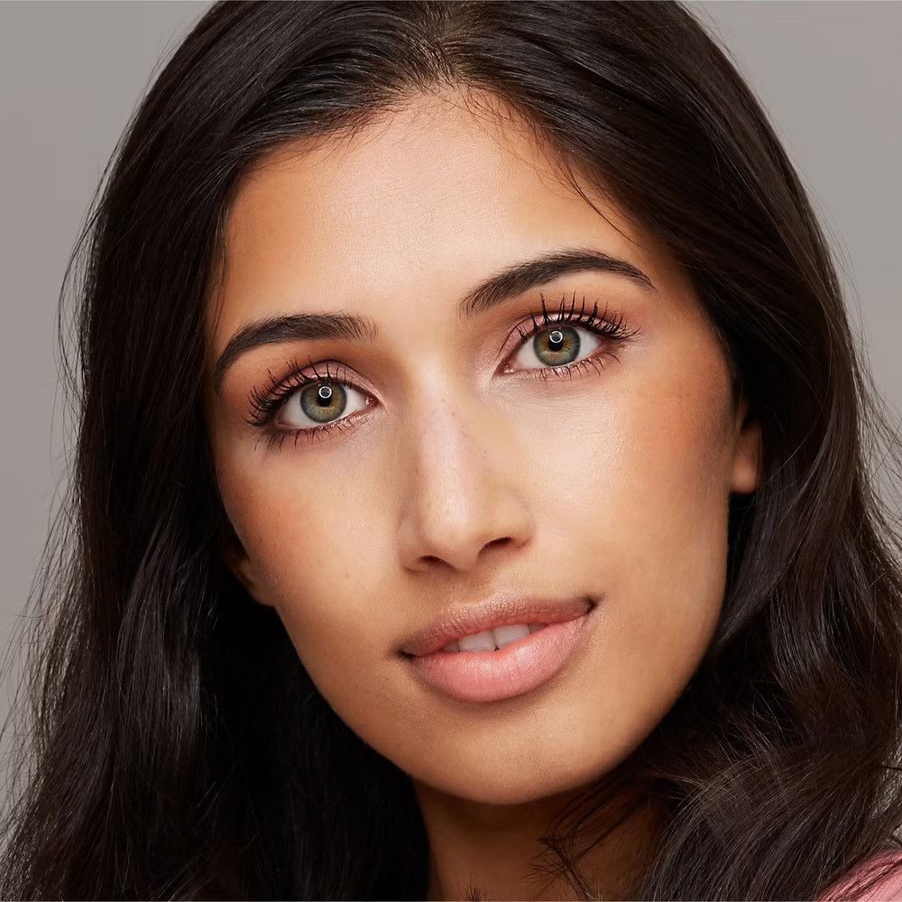 Nahaufnahme einer Frau mit dunklen Haaren. Sie hat grüne Augen und trägt Mascara. Ihr Blick geht in die Kamera.