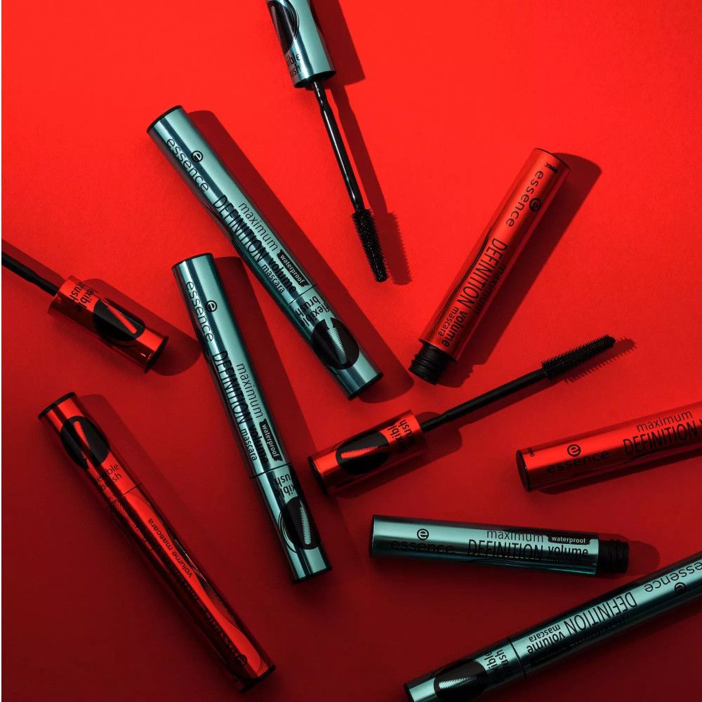 Mehrere Mascaratuben und -bürsten auf rotem Hintergrund. Schwarze Bürsten, türkisfarbene und rote Tuben. Aufschrift: maximum DEFINITION volume mascara.