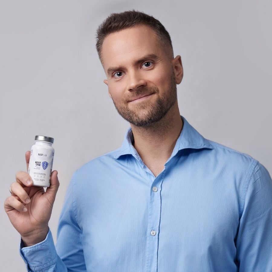 Mann hält kleine weiße Flasche. Aufschrift: BEST LAB BEST ONE. Enthält Vitamin D, K, Magnesium. 60 Kapseln.