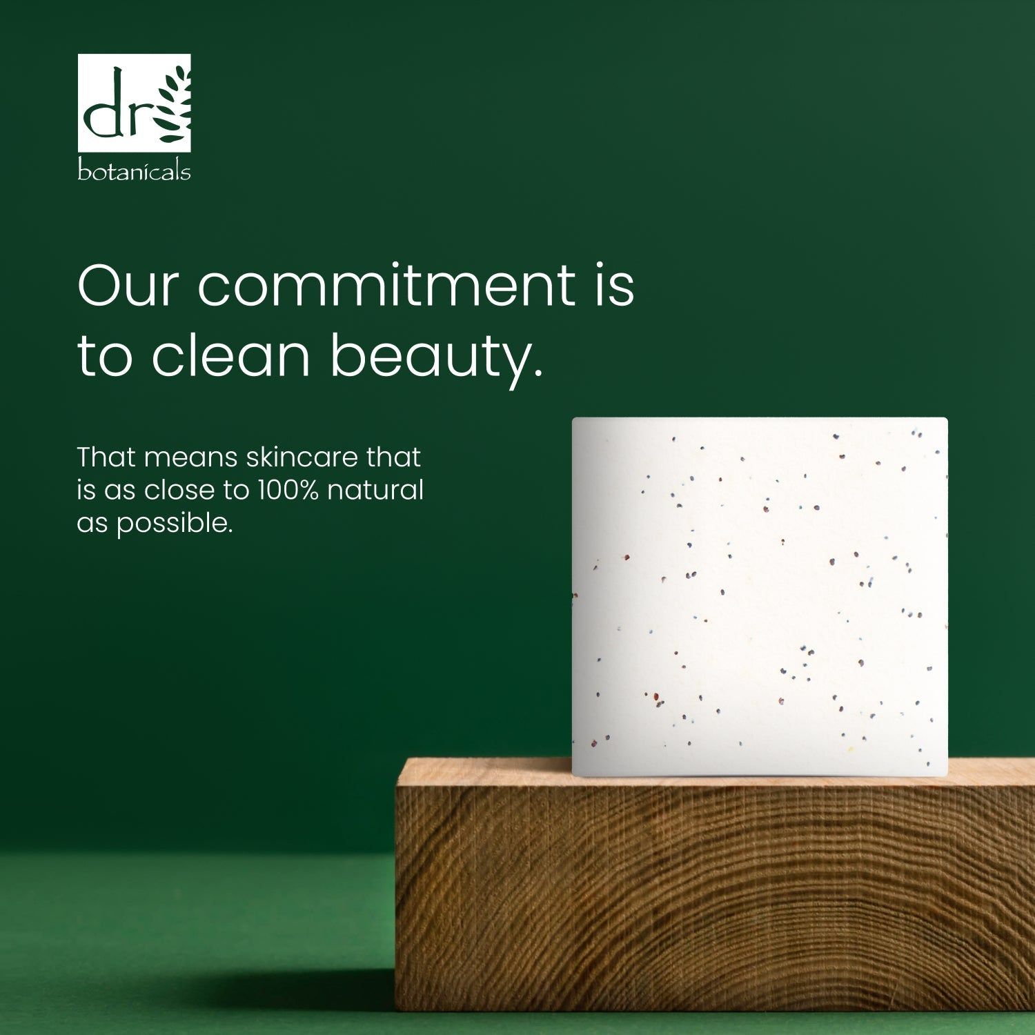 Cremefarbener Block mit dunklen Punkten auf Holzblock. Text: 'Our commitment is to clean beauty'.