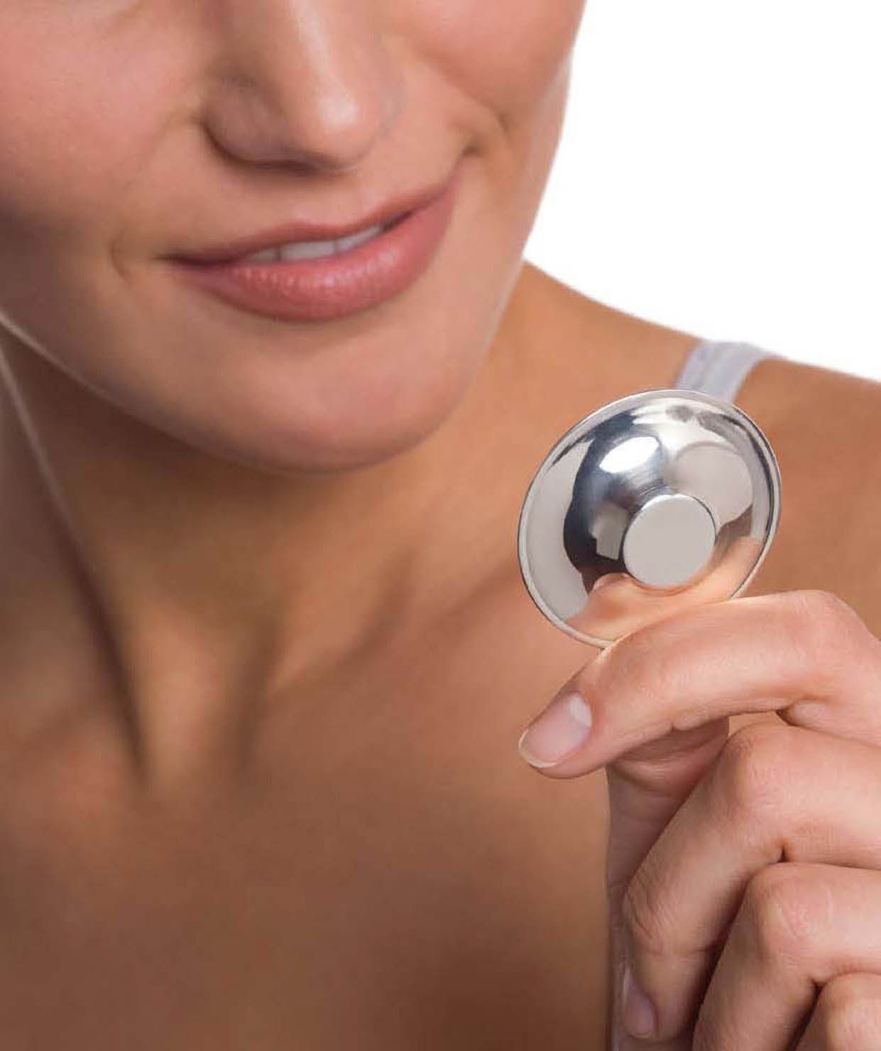 Eine Frau hält einen silberfarbenen Brustwarzen Schützer in der Hand.