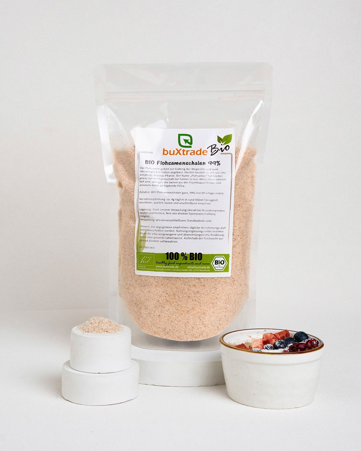 Verpackung mit buXtrade Bio Flohsamenschalen, daneben Schalen und eine Schale mit Brei und Früchten. Bio-Siegel.