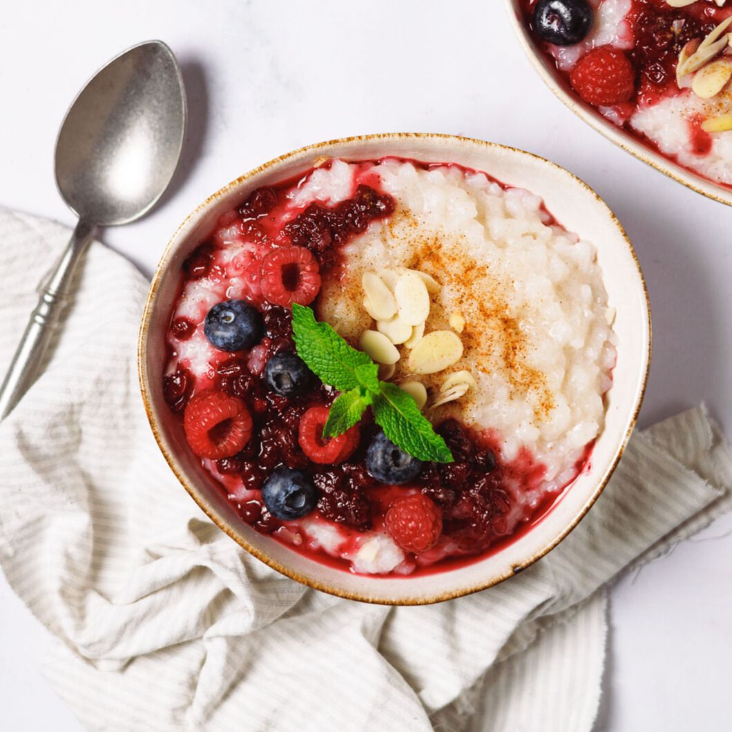 Schüssel mit Reis, Beeren und Mandelsplittern. Draufsicht, serviert mit Löffel.