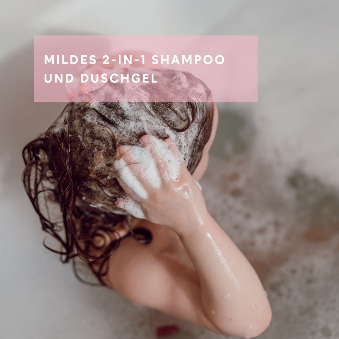 Kind mit Schaum im Haar in einer Badewanne. Text: MILDES 2-IN-1 SHAMPOO UND DUSCHGEL.