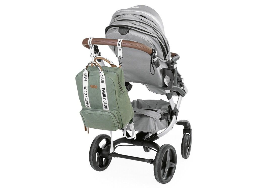 Grüner Wickelrucksack an einem Kinderwagen befestigt. Weiße Träger mit FAMILY CLUB-Schriftzug. Braune Griffe.