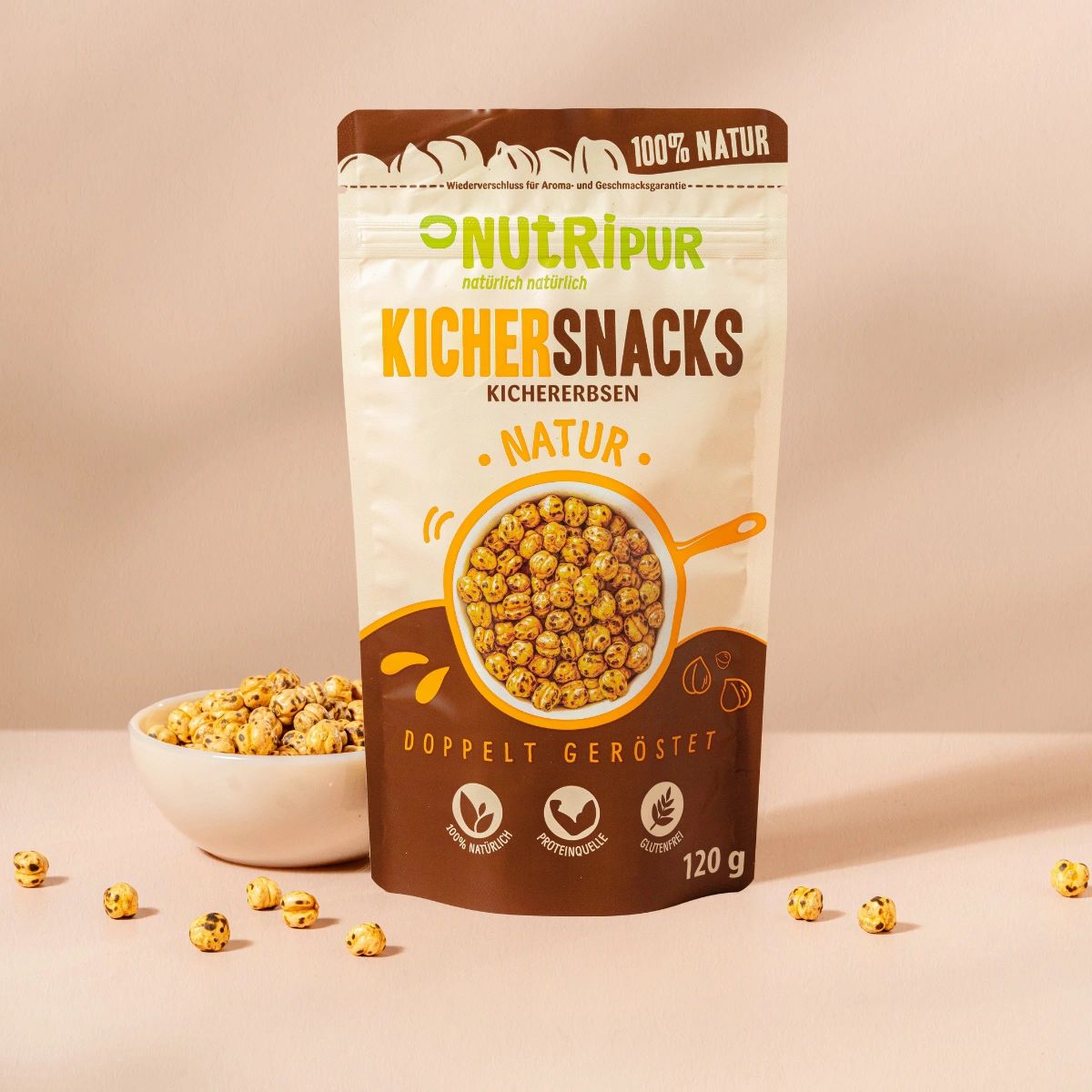 Beutel mit Kichererbsen-Snacks. Aufschrift: NutriPur, Kichererbsen Snacks, Natur, doppelt geröstet. Eine Schüssel mit Kichererbsen daneben.
