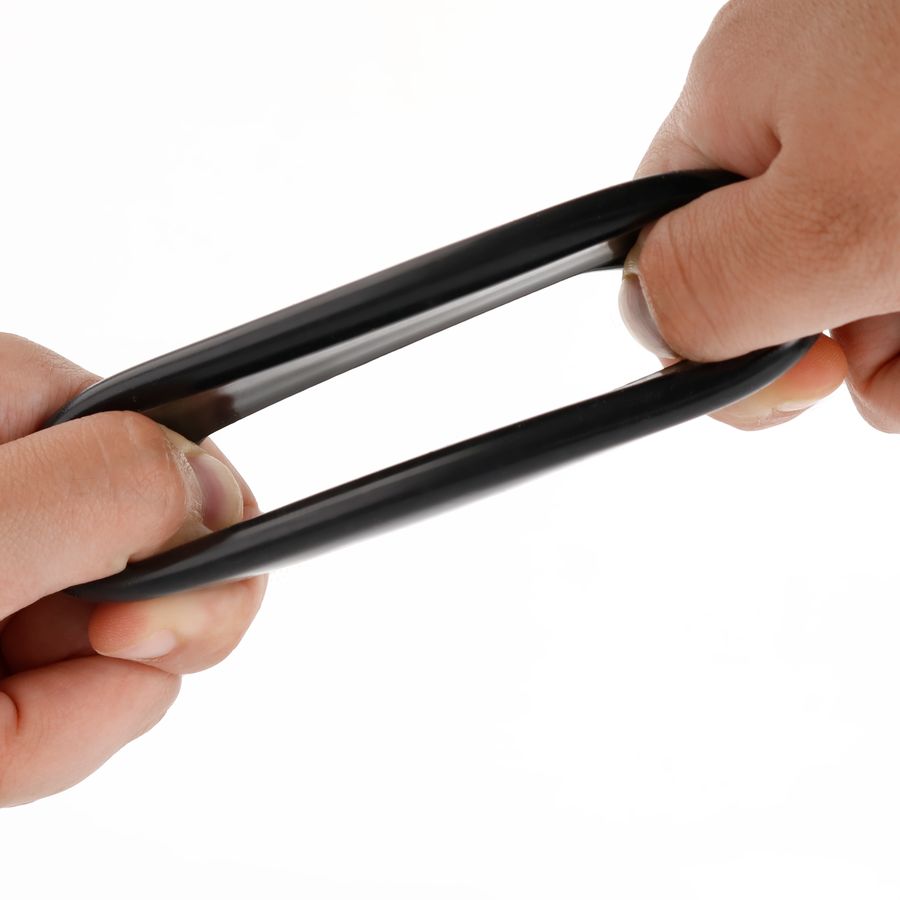 Zwei Hände dehnen einen schwarzen, flexiblen Ring. Der Ring ist aus Gummi oder einem ähnlichen Material gefertigt.