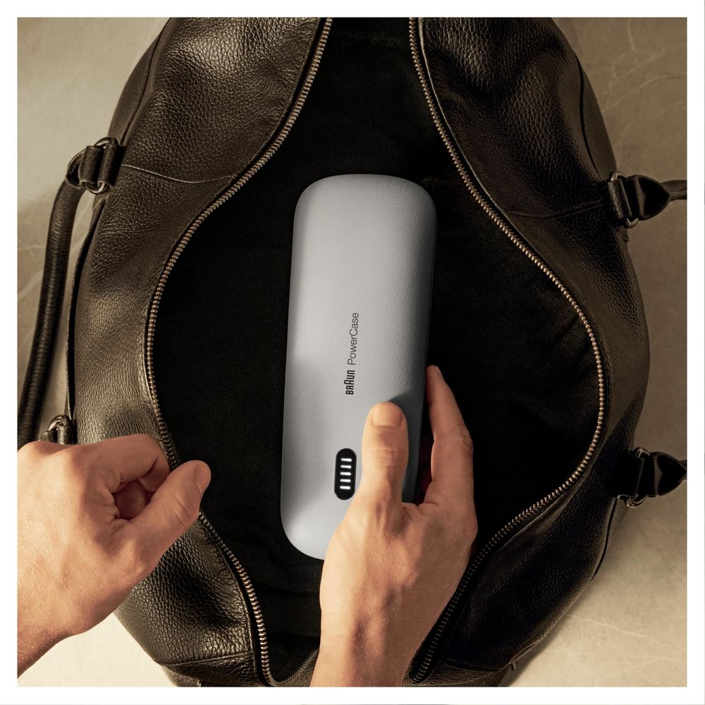 Person hält graues Ladeetui in einer schwarzen Tasche. Auf dem Etui steht "Braun Power Case".
