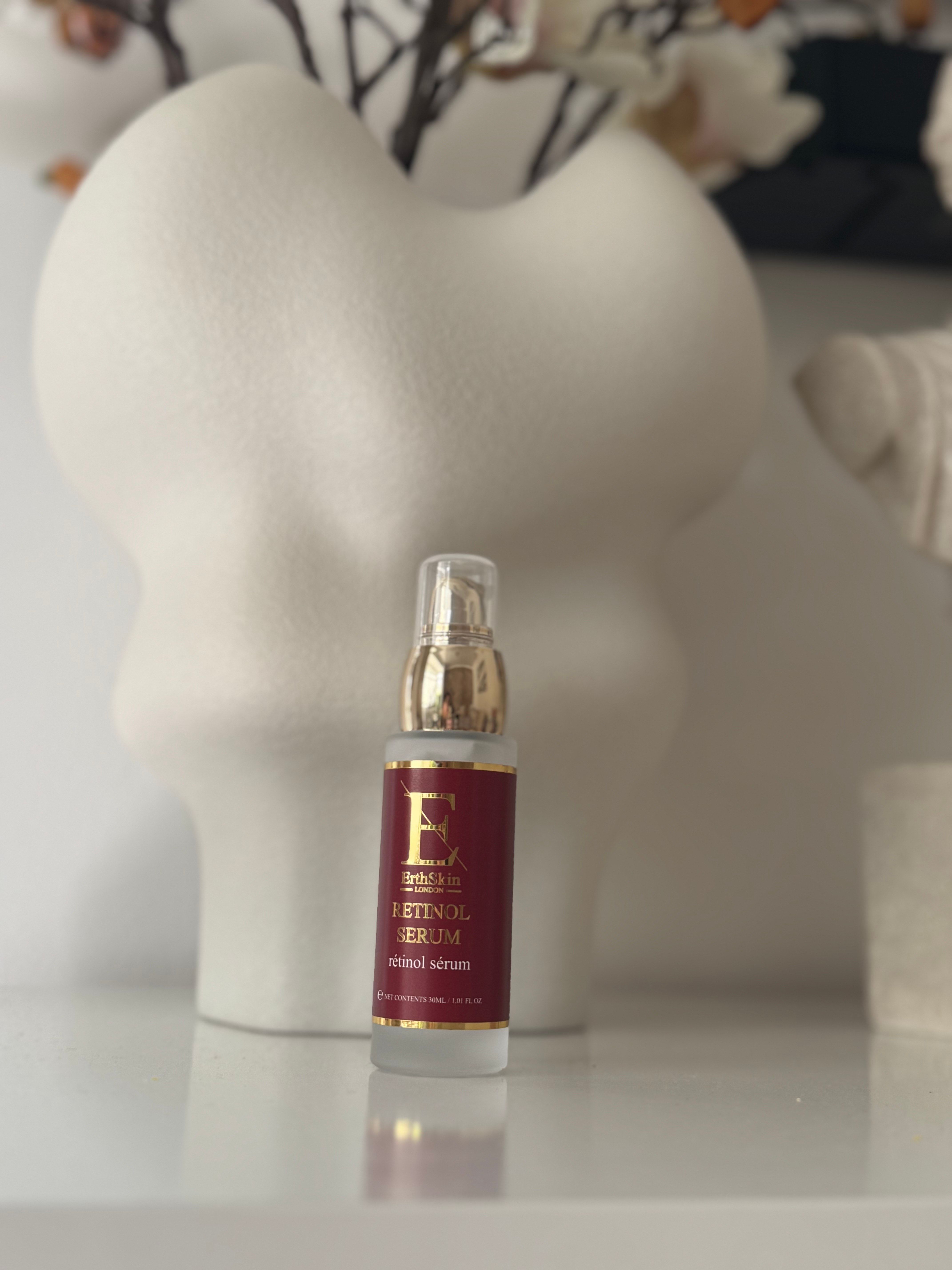 Retinol-Serum-Flasche. Flasche mit Dosierpumpe, rotes Etikett mit goldfarbenem Logo und Text. Auf weißem Hintergrund.