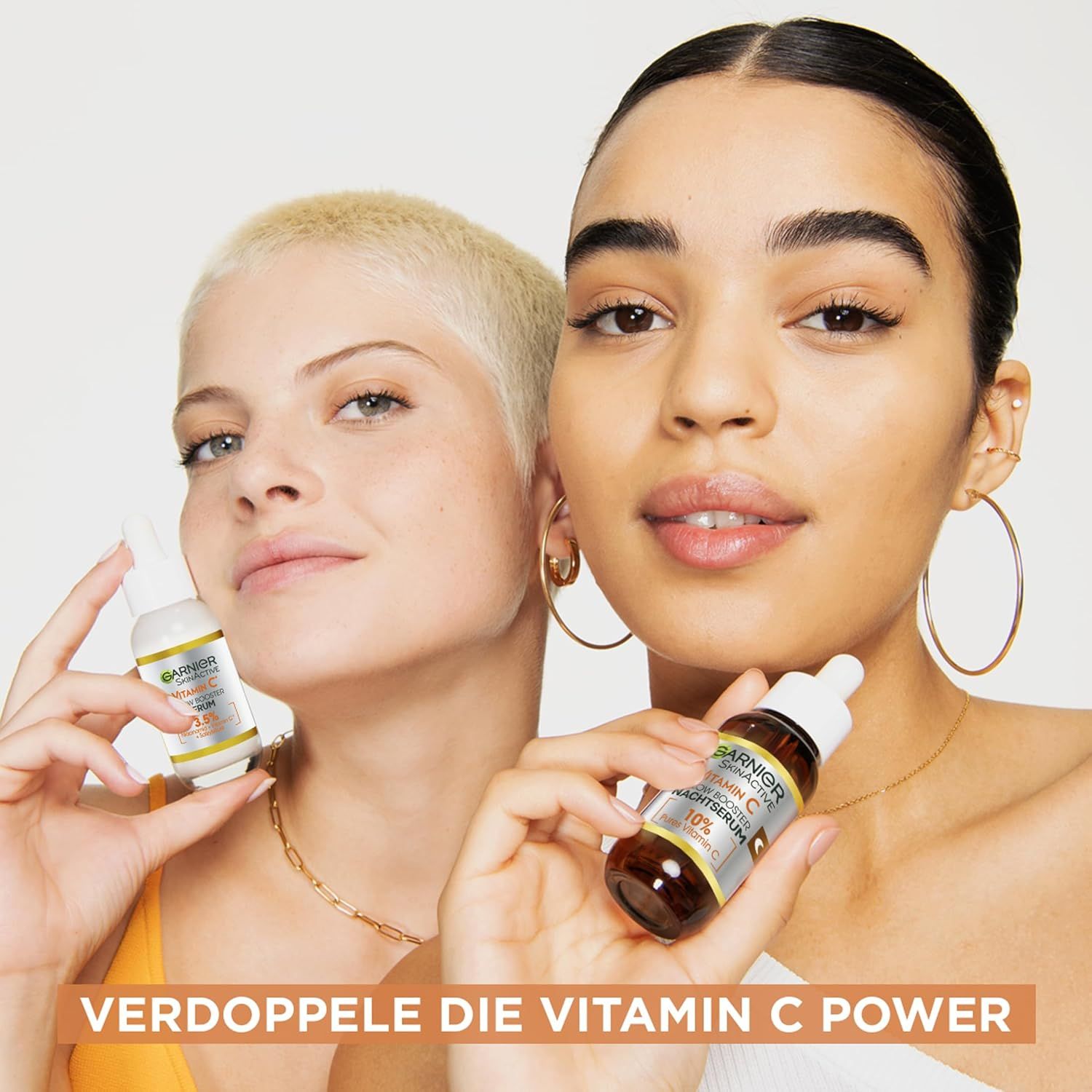 Zwei Frauen halten Serumflaschen. Text: Verdoppele die Vitamin C Power.