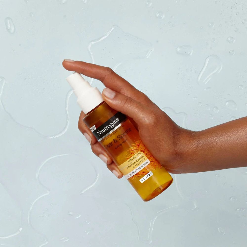 Braune Flüssigkeit in einer Sprühflasche. Die Hand hält die Flasche. Aufschrift: Neutrogena.