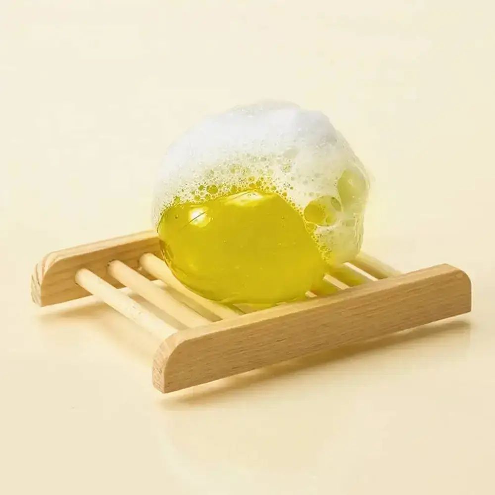 Gelbe Kugel mit Schaum auf einem Holzrost. Draufsicht.