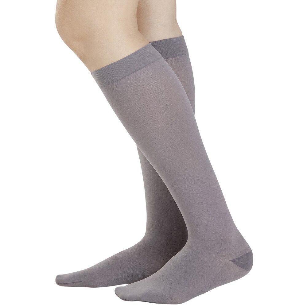 Graue Kompressionsstrümpfe am Bein einer Person. Kniestrümpfe mit verstärkter Spitze und Ferse. Blick von der Seite.