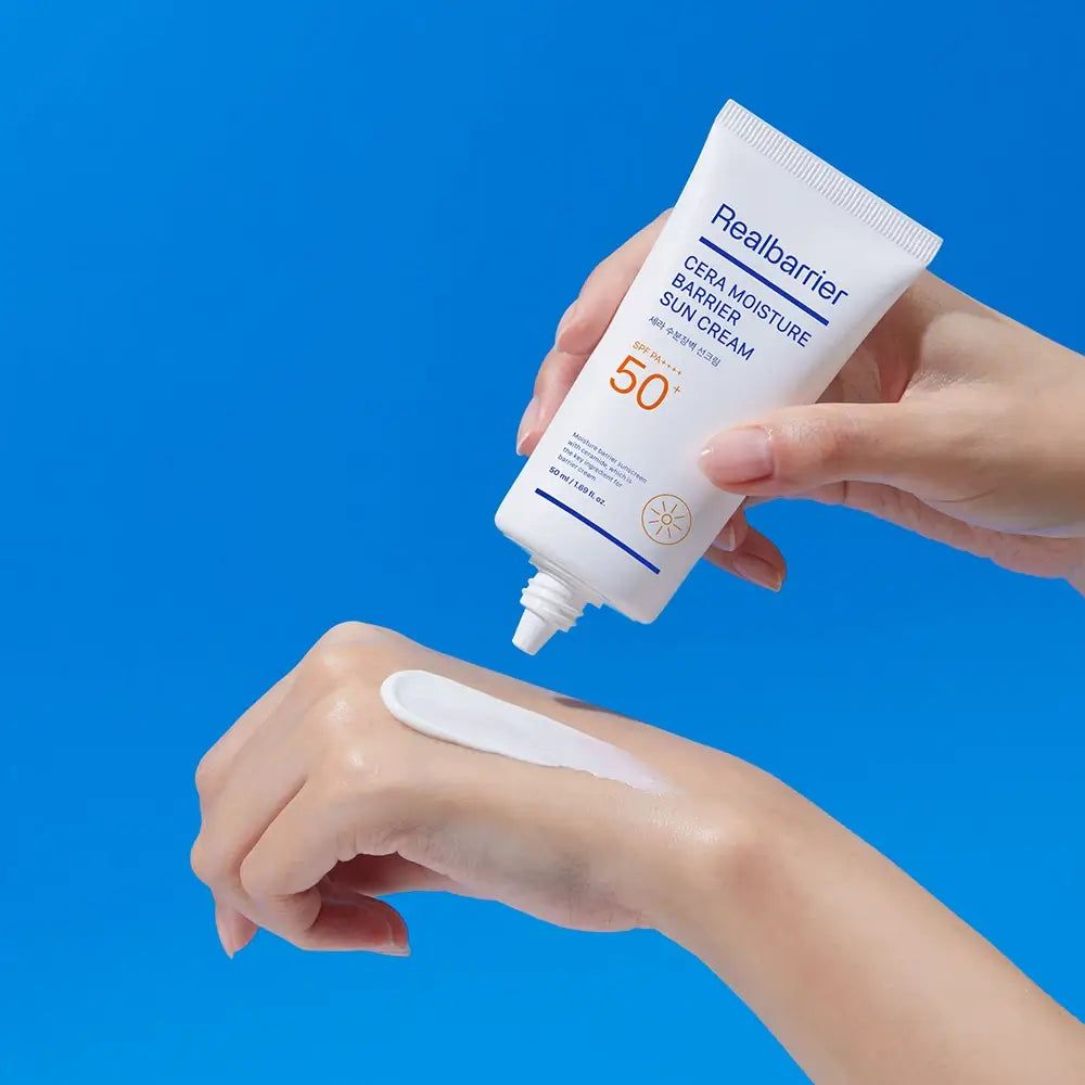 Weiße Tube mit Produkt, das auf die Hand aufgetragen wird. Aufschrift: Realbarrier Cera Moisture Barrier Sun Cream SPF 50. Helle Hautcreme.