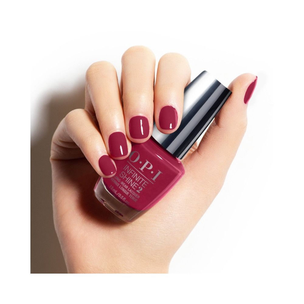 Hand hält eine Flasche Nagellack. Auf den Fingernägeln ist der gleiche Farbton aufgetragen.