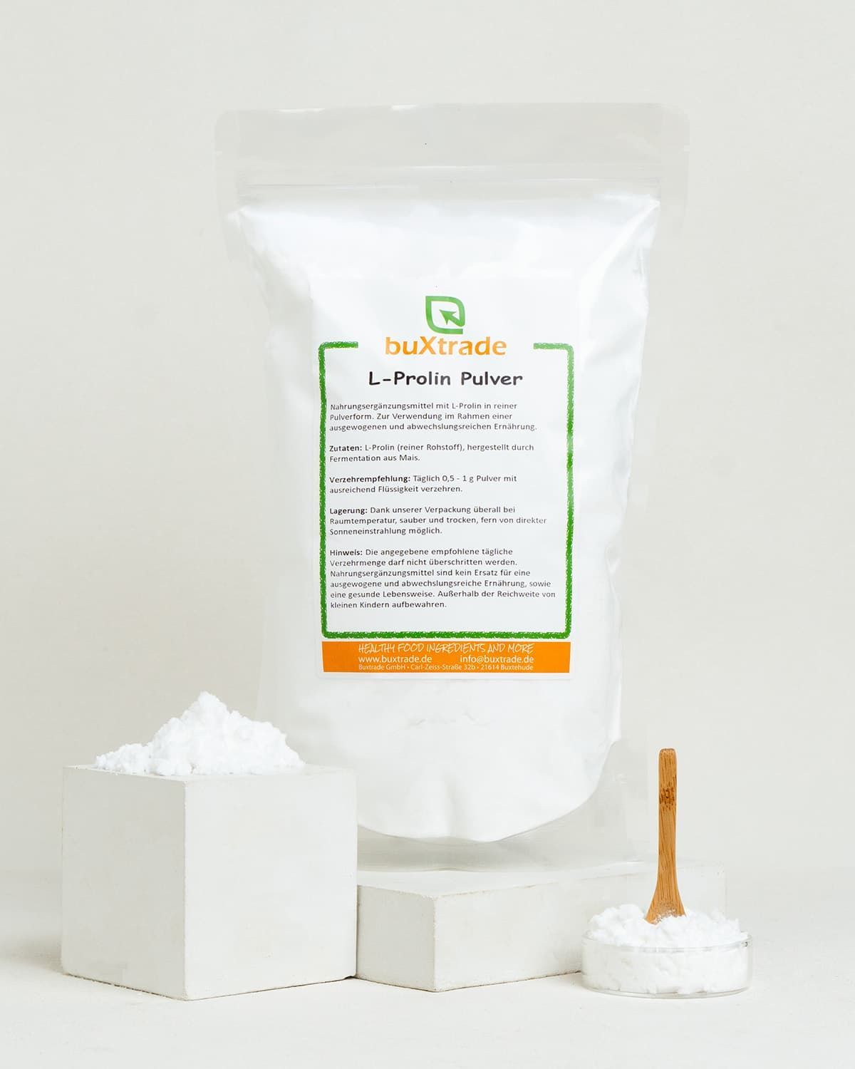 Verpackung mit L-Prolin Pulver, daneben ein Würfel mit Pulver und eine Schale mit Pulver.