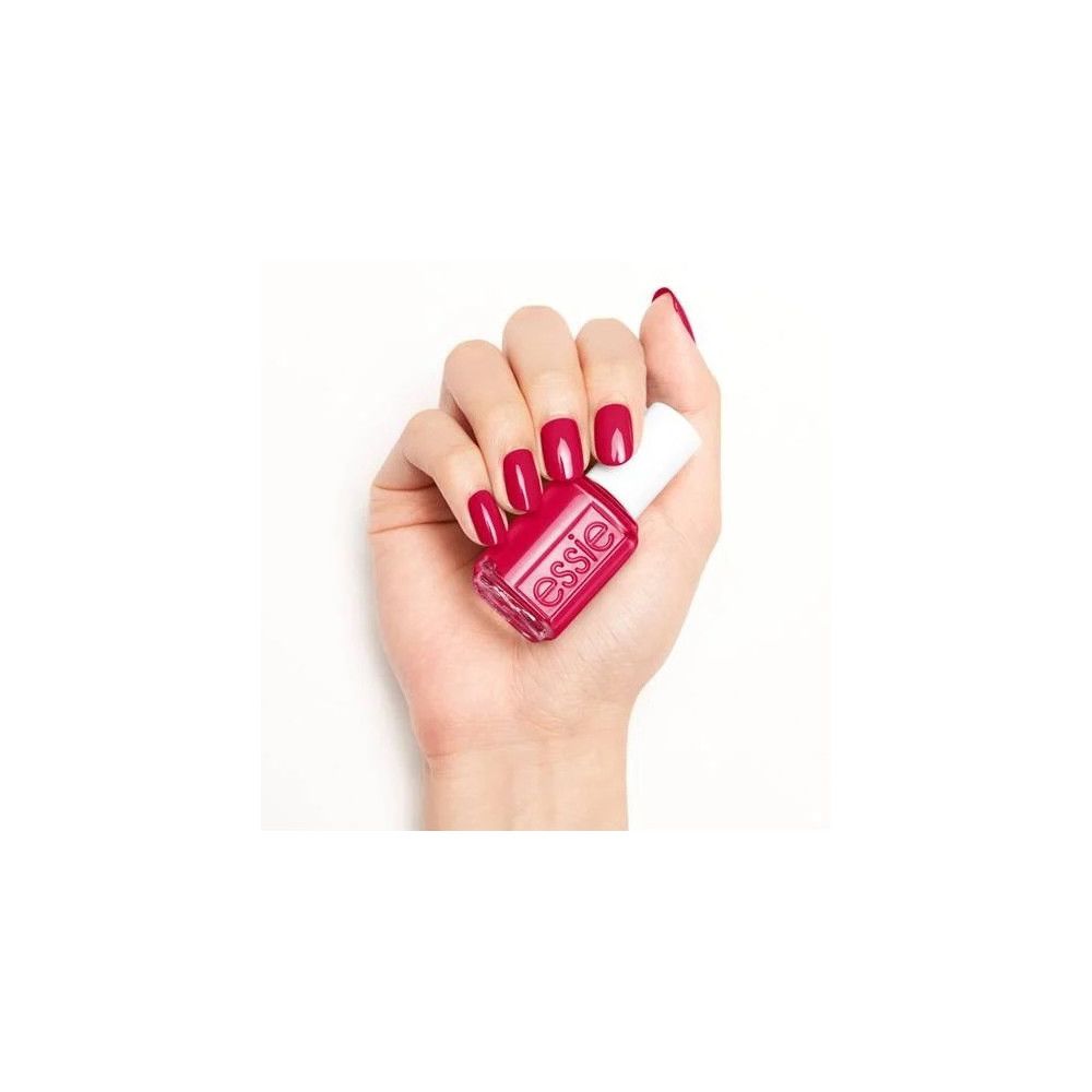 Hand mit lackierten Nägeln und Nagellackflasche. Flasche mit weißem Deckel, roter Lack. Essie-Logo.