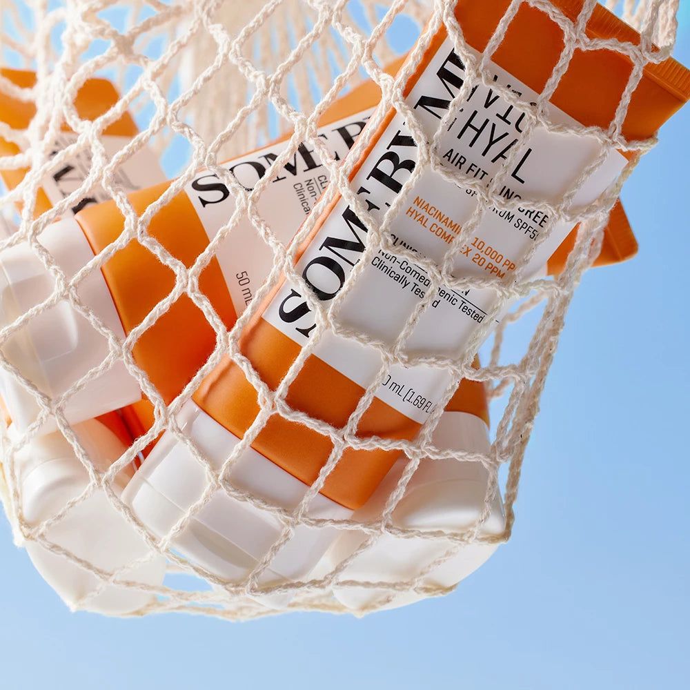 Mehrere orange Tuben in einem Netz. Aufschrift: SOME BY MI V10 Hyal Air Fit Sunscreen SPF50. 50 ml.