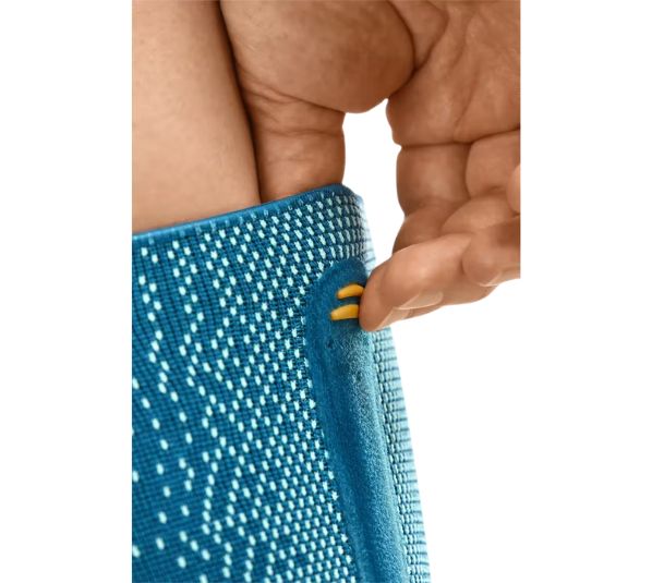 Nahaufnahme der Knieorthese. Detail des Klettverschlusses und gelben Akzents. Blau-türkises Material.