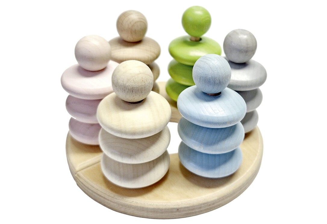 Holzspielzeug mit sechs Türmen in Pastellfarben auf einer runden Holzbasis. Jeder Turm hat Ringe und eine Kugel.